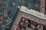 Folded corner of a vintage Indian carpet shows its full dusty teal pile, clean white fringe, and intact side selvage.
