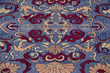 Close-up of the plush, even pile showing Arts and Crafts motifs in red and beige on blue.
