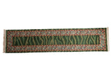 Vintage Indian runner rug with a striated green field and scrolling palmette border in red and blue.