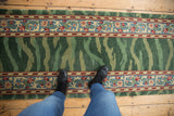 A look down at the vintage runner's striated green pile and scrolling palmette border.