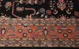 Ornate blossoms on the black field and pale terracotta border of a vintage Sarouk design carpet.
