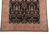 Detail of the ornate terracotta border and floral black field on a vintage Indian Sarouk carpet.