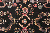 Ornate Sarouk design with blossoms in terra cotta, blue, and mint on a dense black wool pile.