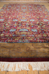 Gold border of the Indian Arts and Crafts rug with pale denim scrolling vines and white fringe.