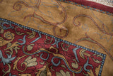 Scrolling leaves and arabesques in wine red, gold, and denim on a vintage Indian carpet.
