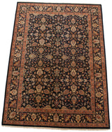 Perspective view of a vintage Indian carpet with intricate lotus and vine motifs on a navy field.