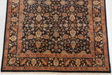 Hand-knotted Indian carpet corner with a terracotta floral border and dense navy blue field.