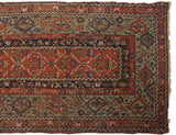 Corner of an antique Fereghan showing the wide signature green border and red lattice field.
