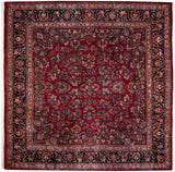 A vintage Sarouk square carpet with a ruby red field, allover floral sprays, and a dark navy blue border.
