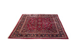 Perspective view across a vintage Persian Sarouk carpet with dense floral bouquets on a ruby red field.