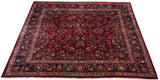 Angled view of a vintage Sarouk carpet, showing gem-tone floral sprays on a ruby red field.