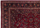 Corner detail of a fine Persian Sarouk rug, showing the intricate navy border and allover ruby floral field.