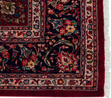 Dense pile and intact red selvage on the corner of a vintage Sarouk rug with floral borders.
