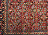 Intricate Herati pattern in cherry red meets the scrolling vinery of the Samovar-style main border.