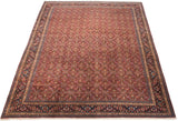 Vintage Tabriz carpet angled to show the dense red Herati field and complex navy border.