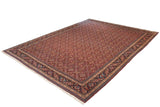 Angled view of a vintage Tabriz carpet with a red Herati pattern and wide navy blue border.