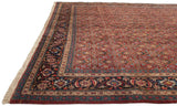Complex border and dense red Herati field on a vintage Tabriz carpet, viewed from a corner angle.