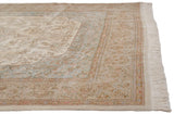 The corner of a vintage Tabriz carpet with a powder blue floral border and neat, full ivory fringe.
