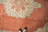 A vintage Tabriz carpet's starburst medallion and corner spandrel on an open terracotta field.