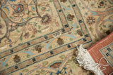 The secured corner of a hand-knotted Tabriz carpet, showing its ivory fringe and terra cotta backing.
