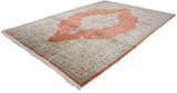 A vintage Persian Tabriz carpet from an angle, highlighting the copper medallion and ivory field.