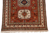 Corner of a vintage Meshkin carpet showing geometric bird motifs, intricate borders, and original ivory fringe.