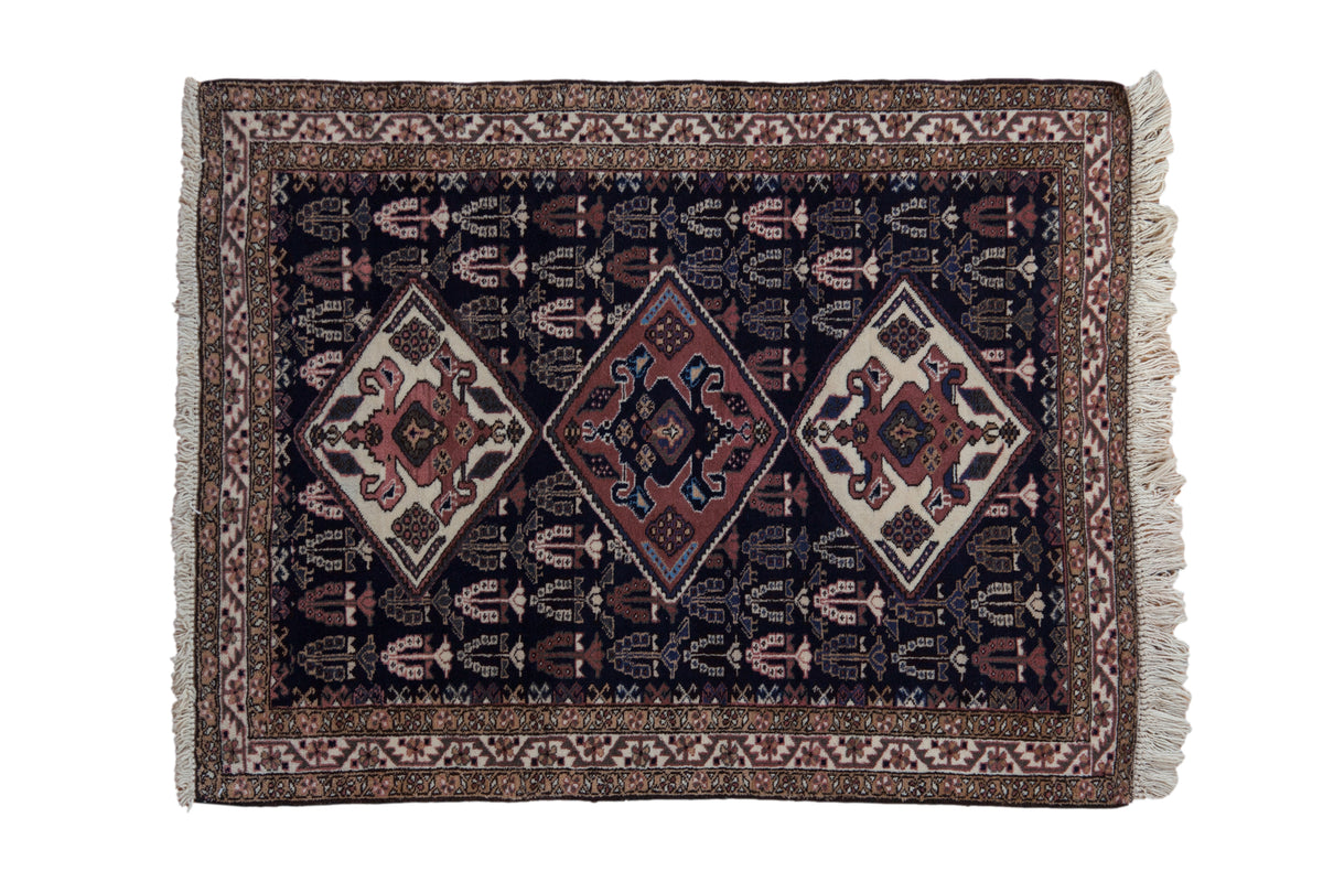 Vintage Ardebil rug with three interconnected diamond medallions in terra cotta and ivory on a deep navy blue field.