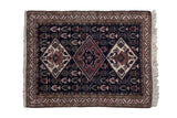 Vintage Ardebil rug with three interconnected diamond medallions in terra cotta and ivory on a deep navy blue field.