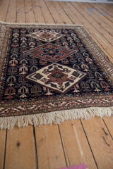 Angled view of a vintage Ardebil rug showing its geometric diamond pattern and thick pile.
