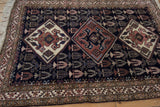 Angled corner view of a vintage Ardebil rug highlighting its plush pile and ivory fringe.
