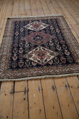 Angled view of a vintage Ardebil rug with interconnected diamond medallions.