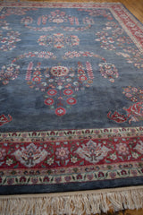 Laristan carpet detail: dusty denim blue field, cherry red floral border, and ivory fringe.