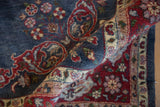 Vintage Laristan carpet's full pile texture and detailed millefleur blossoms in denim blue and red.