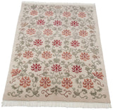 Angled view of an Indian Arts and Crafts carpet with cherry red lotus flowers and green vinery.