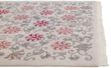 Corner of an Indian Arts and Crafts carpet showing the textured pile, floral pattern, and clean ivory fringe.