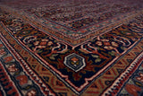 Plush navy blue and dusty raspberry floral borders on a vintage Indian Bijar rug corner.