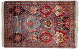 Vintage Agra rug showing a covered field of staggered palmettes and arabesques in blue and red.