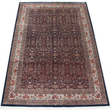 Angled view of a vintage Indian carpet highlighting the intricate allover floral design against a dark navy blue field.