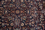 Intricate floral cross-sections and vinery motifs on the vintage carpet's deep navy blue pile.