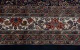 Trefoil rose florals and scrolling vinery on the ivory main border of a vintage Indian carpet.