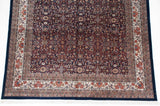 Vintage Indian carpet corner showing the detailed navy field and wide ivory and red floral border.