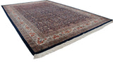 Angled view of a vintage Indian carpet showing the balanced floral design on its vast navy blue field.