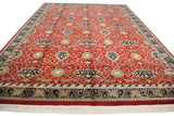 Angled perspective of a vintage Indian carpet's cherry red field with allover rose and vinery motifs.