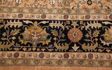 The Heriz carpet's intricate border with floral motifs in gold and copper on a navy blue ground.