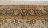 A close view of the Agra carpet's Herati border in dusty green and gold, with full ivory fringe.