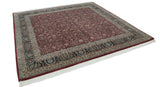 Angled view of a square Tabriz design rug with a cherry red allover pattern and dark navy border.
