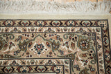 Detailed corner of a square Isfahan carpet showing the floral border and ivory fringe.