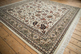 Angled corner view of an Indian Isfahan rug detailing the floral border and soft ivory wool pile.
