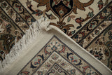 Corner of Indian rug folded over, revealing the dense hand-knotted foundation and clean ivory fringe.