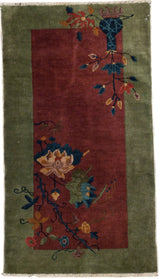 Dark blue potted plant tree-of-life with blossoming vines on a burgundy Art Deco rug.